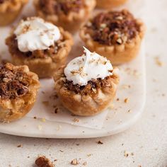 small desserts are sitting on a plate with whipped cream and pecans scattered around them