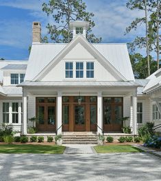 a white house with brown doors and windows on the front porch is featured in this image