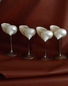 four small white vases sitting on top of a brown cloth