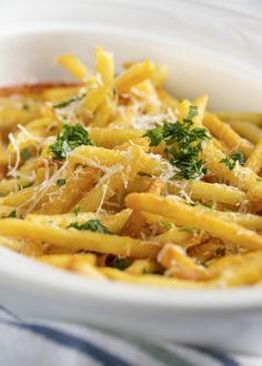 a white bowl filled with pasta covered in parmesan cheese and parsley sprinkled on top