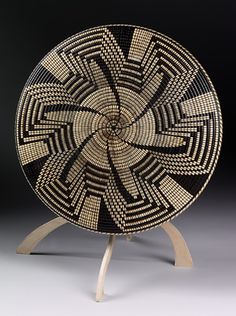 a black and white basket sitting on top of a wooden stand