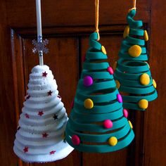 three paper christmas trees hanging from hooks on a door