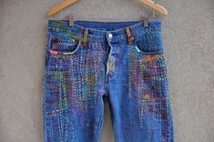 a pair of blue jeans with colorful patches on them