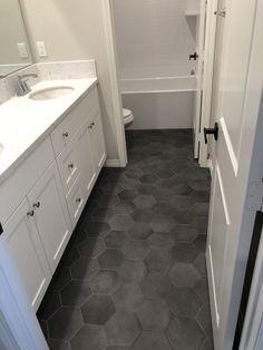 a white bathroom with gray hexagonal tile flooring