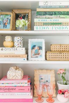 books, vases and pictures are sitting on the shelves