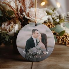 an ornament with a photo of a bride and groom on it next to flowers