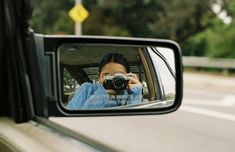 a woman taking a photo in the rear view mirror of a car with her camera