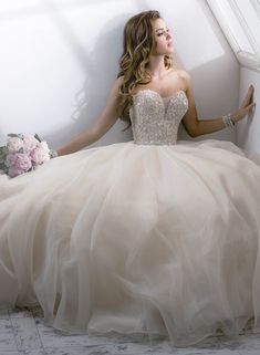 a woman in a wedding dress sitting on the floor