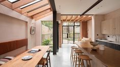 an open kitchen and dining room area with wooden furniture, windows, and skylights