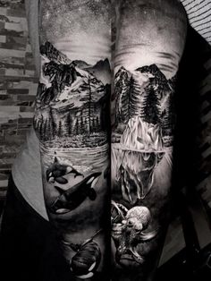 a man's leg with tattoos on it and mountains in the background, while he is