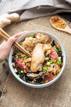 someone holding chopsticks over a bowl of food with mushrooms and other foods in it