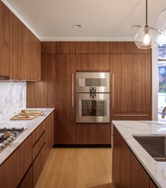 a kitchen with wooden cabinets and marble counter tops, stainless steel appliances and an oven