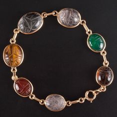 14k Yellow Gold Oval Cabochon Scarab Style Multi-Stone Bracelet 11.05gMetal Information: 14k Yellow GoldTotal Weight: 11.05gBracelet Width: 13mm - 3.5mmBracelet Length: 7.5"Stone InformationMain StoneGem Type: QuartzShape: Oval Cabochon (15.7mm x 11.75mm)Color: ClearClarity/Quality: ANumber of Stones: 1Accent StonesGem Type: QuartzShape: Oval Cabochon (13.2mm x 11.2mm / 11.8mm x 9.9mm)Color: Pink ClearClarity/Quality: ANumber of Stones: 2Accent StonesGem Type: AgateShape: Oval Cabochon (11.5mm x 9.4mm)Color: RedClarity/Quality: ANumber of Stones: 1Accent StonesGem Type: AgateShape: Oval Cabochon (11.5mm x 9.8mm)Color: Orange RedClarity/Quality: ANumber of Stones: 1Accent StonesGem Type: Tigers EyeShape: Oval Cabochon (13.7mm x 11.4mm)Color: BrownClarity/Quality: ANumber of Stones: 1Accent Luxury Oval Cabochons With Center Stone, Luxury Platinum Oval Cabochon Jewelry, Luxury Oval Cabochon Brooch Jewelry, Luxury Amber Beads Gems And Cabochons, Luxury Gold Oval Cabochons, Luxury Handmade Vintage Beads, Gems And Cabochons, Luxury Engraved Oval Cabochon Jewelry, Deep Autumn Palette, Stone Jewellery