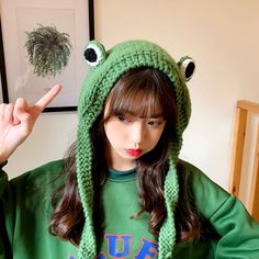 a woman wearing a green frog hat and scarf