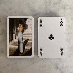 two playing cards sitting on top of a marble table next to each other, one with an image of a woman