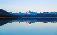 the mountains are reflected in the still water