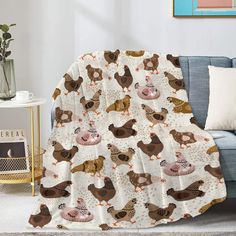 a living room with a blue couch and a white blanket covered in chickens on it