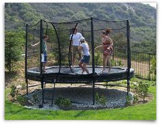 three children are playing on a trampoline in the park