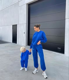 a woman holding the hand of a small child in front of a large garage door