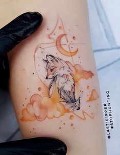 a woman's thigh with a watercolor tattoo of a fox and the moon