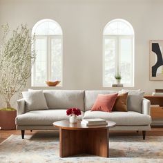 a living room with two windows and a couch in front of the window is a coffee table