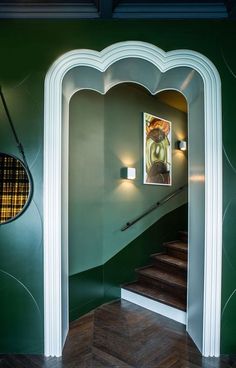 an entry way with green walls and wood flooring in the center, along with a painting on the wall