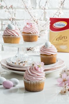 three cupcakes with pink frosting and white chocolate eggs on a cake plate