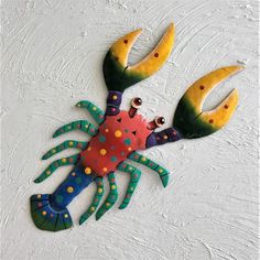 a colorful crab made out of paper on a white surface with yellow and blue dots