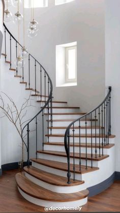 a spiral staircase in a home with wood floors and white walls, along with glass chandeliers