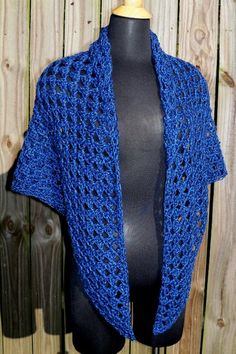 a blue crocheted shawl on top of a mannequin dummy next to a wooden fence