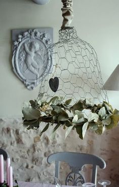 a dining room table and chairs with flowers in the vases hanging from the chandelier