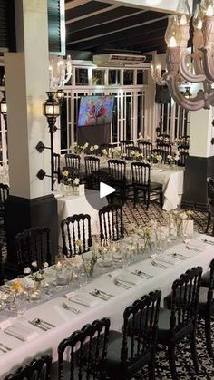 a long table set up for an event with chandeliers and white linens