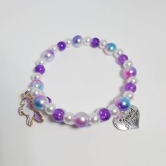 She will feel magical in this sweet unicorn beaded bracelet.  It is made with purple glass beads, with rainbow and white faux pearls. It is a memory wire wrap bracelet so it will fit a wide range of sizes.  It has a Tibetan Silver Granddaughter charm and an Enamel Unicorn Charm. The charms can be switched for any of those pictured, if requested. All of my items are handmade in Prince Edward Island, Canada. Shipping Information Shipping to Canada is by letter mail and usually takes about 10 days Adjustable Purple Charm Bracelet For Birthday, Purple Letter Beads For Jewelry Making, Purple Beaded Charm Bracelet For Friendship, Adjustable Purple Stretch Bracelet For Birthday, Personalized Purple Charm Bracelet For Friendship, Cute Purple Jewelry For Friendship, Adjustable Purple Jewelry For Birthday, Purple Beaded Bracelet For Birthday, Purple Beaded Bracelets For Birthday