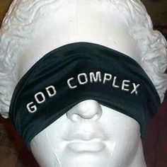 a white mannequin wearing a black headband with the words god complex on it