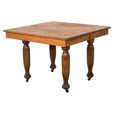 an old wooden table with two turned legs and a small square top on casteors