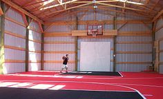 a man is playing basketball in an indoor gym with red and black flooring on the court