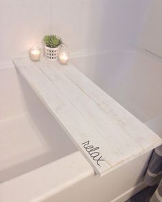 a white bath tub with candles on the side and a wooden shelf in front of it