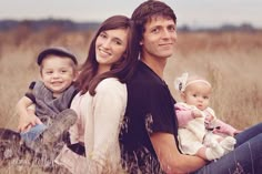 a man, woman and child sitting in tall grass