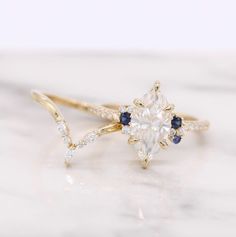 a diamond and blue sapphire ring on top of a marble countertop with white background