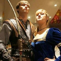 a man and woman dressed up in medieval costumes standing next to each other with swords