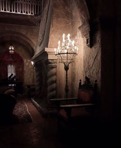 a chandelier hanging from the ceiling in a room with stone walls and flooring