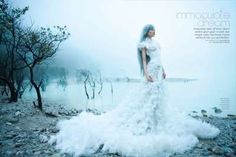 a woman in a white wedding dress standing on rocks