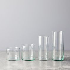 three clear glass vases sitting on top of a gray counter next to each other