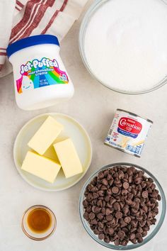 ingredients to make chocolate fudges laid out on a white counter top, including milk, butter, sugar and raisins