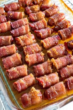 bacon wrapped up in strips on a baking sheet ready to go into the oven for cooking