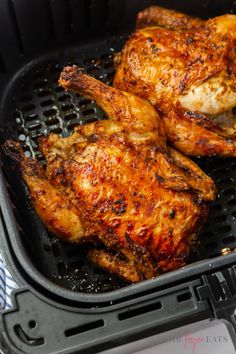 two pieces of chicken sitting on top of an air fryer pan with the lid open