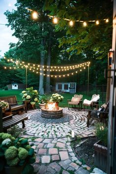 an outdoor fire pit with lights strung over it and chairs around the firepit area