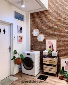 a washer and dryer sitting in a room next to a brick wall with potted plants on it