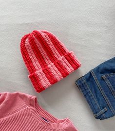 two knitted hats and jeans laid out on a white surface next to each other