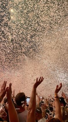 a group of people standing around each other with their hands in the air and confetti falling from the ceiling